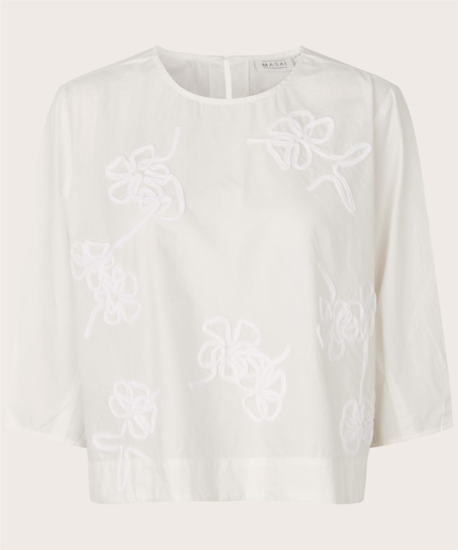 Enkel bluse i bomull med fine applikasjoner.